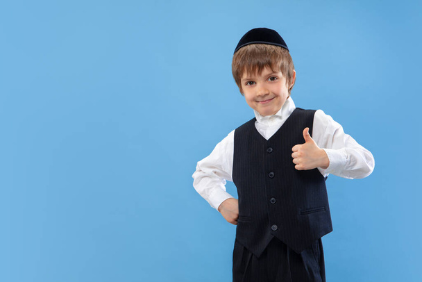 Portrait of a young orthodox jewish boy isolated on blue studio background, meeting the Passover - Фото, зображення
