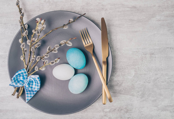 Easter table setting with grey plate and blue eggs on grey wooden table.  - 写真・画像