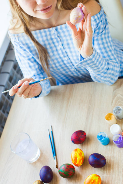 Праздники, ручная работа и создание концепции - Счастливая молодая женщина рисует на Пасхальное яйцо, крупным планом
. - Фото, изображение