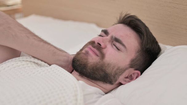 Jeune homme endormi ayant mal au cou au lit
 - Photo, image
