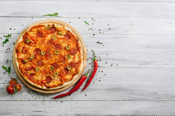 Pizza Pepperoni with mozzarella, salami, pepper and olives on the white wooden background - Foto, Imagem