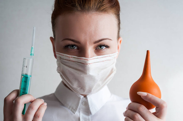 Retrato de uma menina em uma máscara médica. A segurar uma seringa na mão. Fechar u
 - Foto, Imagem