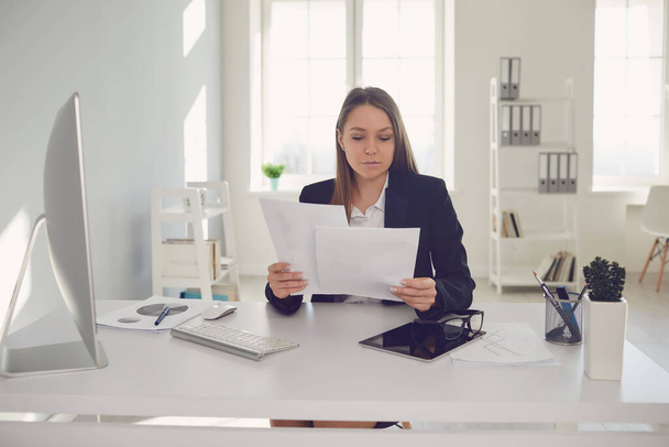 Happy businesswoman with documents in hands sitting at table - Фото, изображение