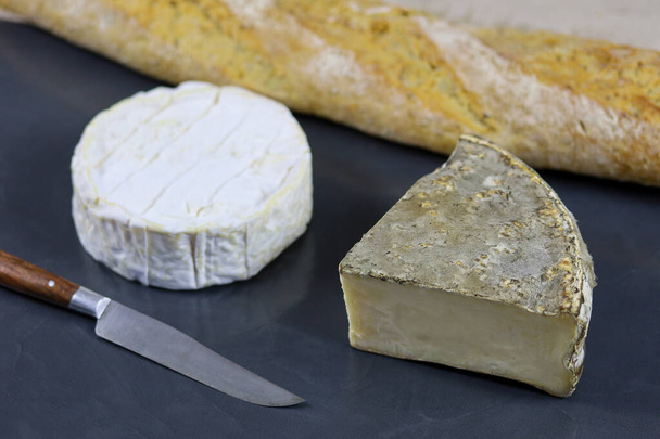 Camembert and Tomme de Savoie (French cheese) on a slate and baguette - 写真・画像