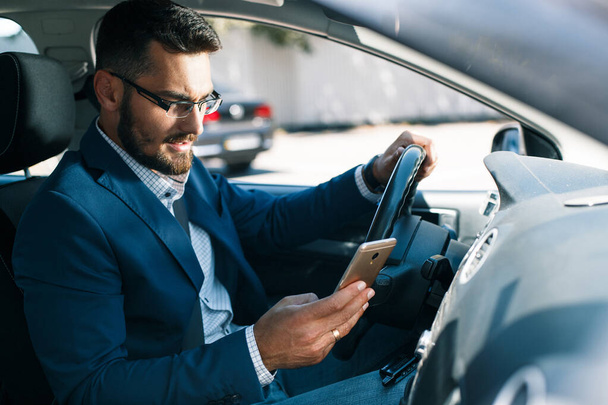 Häiriintynyt nuori liikemies puhelin kädessään istuu autossa
 - Valokuva, kuva