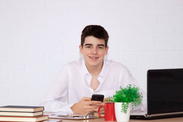adolescent garçon étudiant au bureau avec des annuaires téléphoniques mobiles et ordinateur portable
 - Photo, image