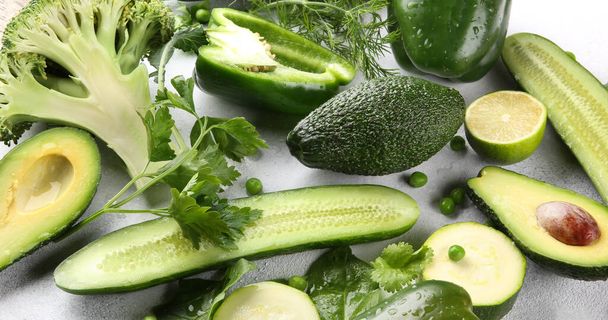 Green vegetables, fruits and herbs on a light background. Fresh pepper, zucchini, peas, cucumber, avocado, lime, broccoli, parsley, dill and spinach. Foodbackground. Background image - Foto, immagini