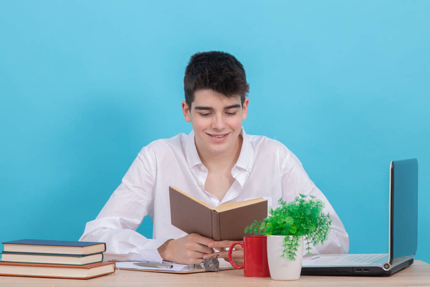 fiatal férfi diák az íróasztalnál könyv és számítógép tanul - Fotó, kép