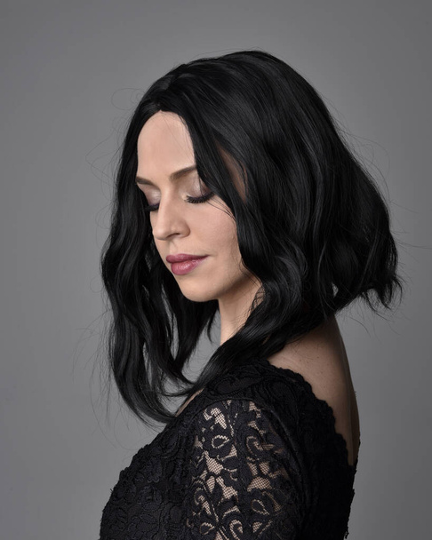 Close up portrait of a pretty, goth girl with dark hair  posing in front  a studio background. - Фото, зображення
