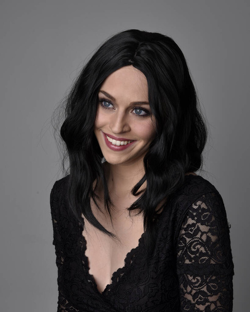 Retrato de cerca de una guapa chica gótica con el pelo oscuro posando frente a un fondo de estudio
. - Foto, imagen