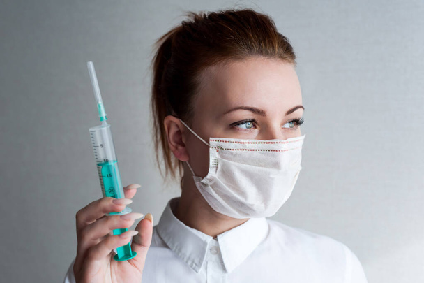 Portrait of a girl in a medical mask. Holding a syringe in her hand. Close u - Photo, Image