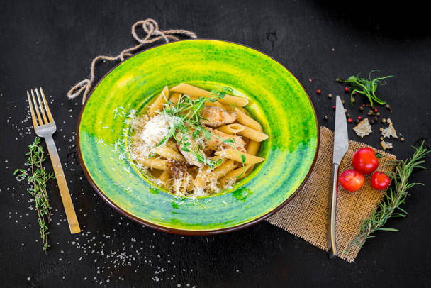 Delicious pasta with cheese in green plate on black wooden board - Photo, Image
