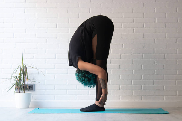 atleet vrouw doet gymnastische oefeningen of stretching thuis of in de sportschool - Foto, afbeelding