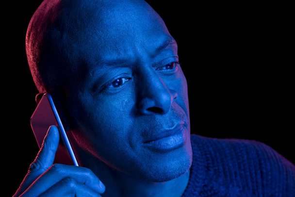 Lähikuva muotokuva sininen ja punainen valot afrikkalainen amerikkalainen mies älypuhelin. Eristetty mustalla pohjalla kopiokoneella
. - Valokuva, kuva