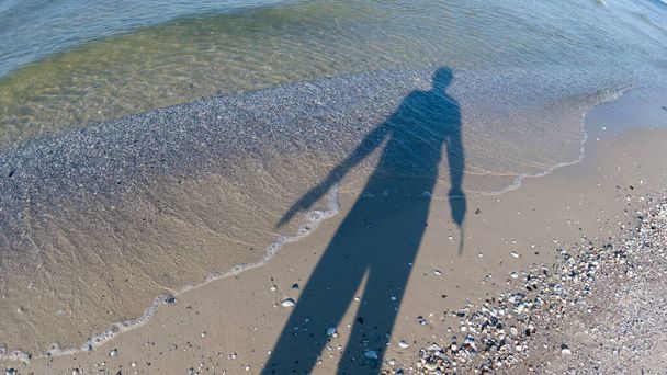 The shadow of a man who sunbathes in the sun on the beach - Foto, afbeelding
