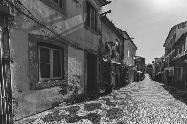 Намотка узкой булыжной аллеи между традиционными ветхими и отремонтированными каменными домами в Кашкайш Португалия
. - Фото, изображение