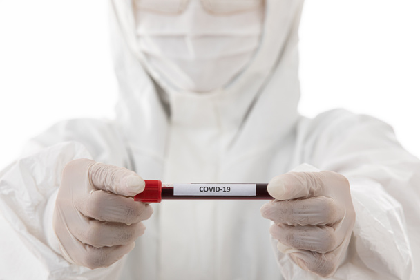 Cientista em esteriliza pano de jaleco segurando amostra de tubo de teste Covid-19 na mão. Foco seletivo no nome do vírus. Conceito para pessoas médicas tentando e pesquisando para ganhar coronavírus. - Foto, Imagem