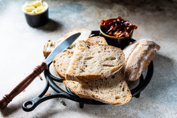 Bakery, crusty loaves of bread. Still life captured from above top view, flat lay . sun-dried tomatoes. Vegetarian food. Healthy food concept. Butter. Sandwich. sourdough bread - Photo, Image