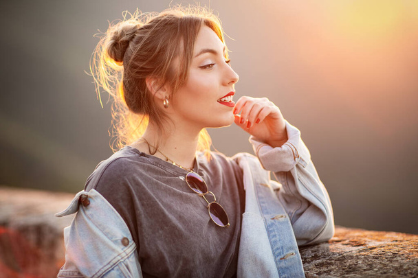 Radosna młoda kobieta w modnym stroju casual uśmiecha się i odwraca wzrok w słoneczny dzień - Zdjęcie, obraz