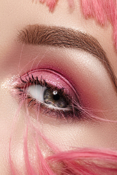 Closeup Macro of Pink Fashion Eye Make-up. Expressive Makeup, Bright Summer Eyeshadows and Magenta Color Hair, Shiny Skin - Foto, Imagen