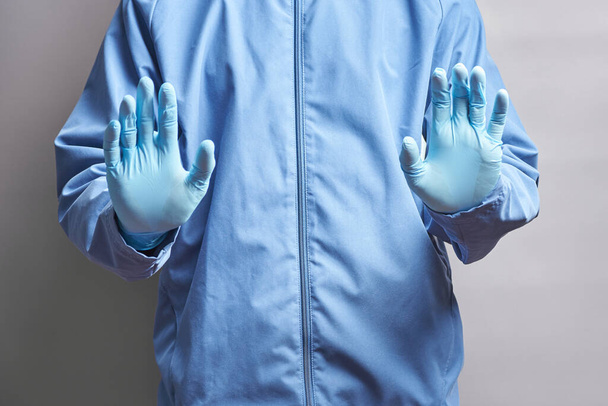 Arzt in Gummihandschuhen hält seine Hände vor sich. Mediziner zeigt ein Stoppschild. Konzept - Foto, Bild