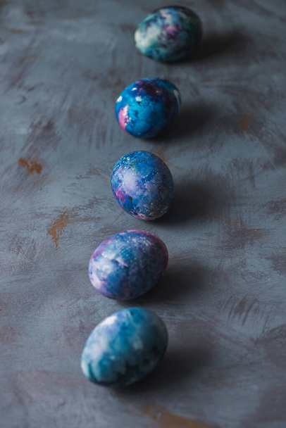 Пасхальный праздник. Пасхальные красочные праздничные яйца на голубой поверхности
. - Фото, изображение