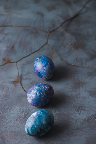 Easter holiday. Easter painted colorful eggs and branch on a blue background. - Foto, Imagem
