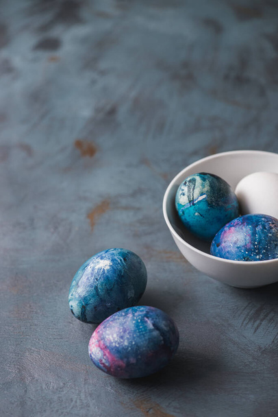Пасхальные яйца, написанные вручную яркими красками. Синий текстурированный фон
. - Фото, изображение