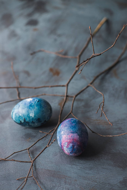 Huevos coloridos pintados de Pascua y rama seca. Fondo azul
. - Foto, Imagen
