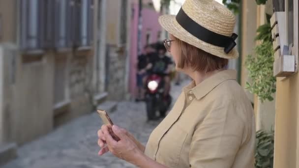 Idős nő mobil a város utcájában - Felvétel, videó
