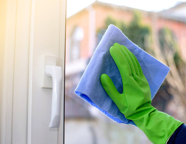 Cleaning of closed vinyl window. Protective glove on hand and cleaning cloth - Photo, image