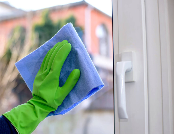 Cleaning of closed vinyl window. Protective glove on hand and cleaning cloth - Фото, изображение