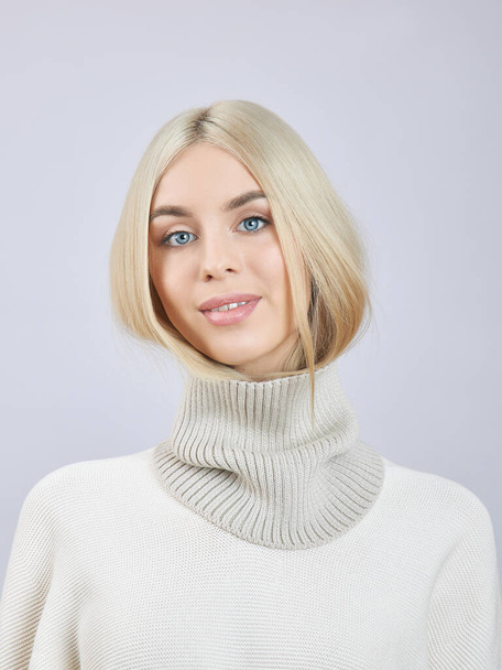 Blonde woman with long hair in a white sweater. Beauty portrait of a girl, natural cosmetics - Foto, Bild