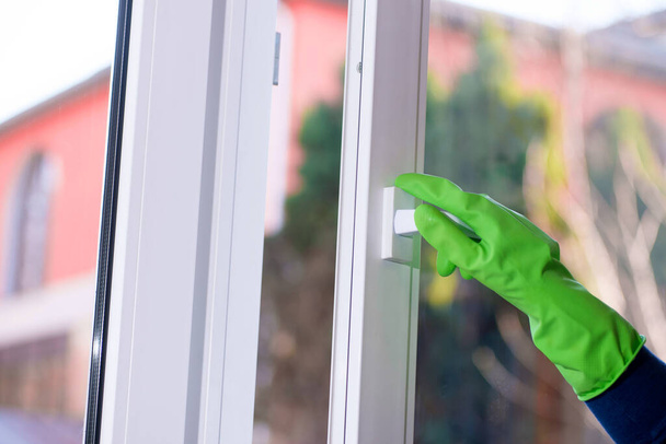 hand opens plastic vinyl window on a blurred background. protective glove on hand - 写真・画像