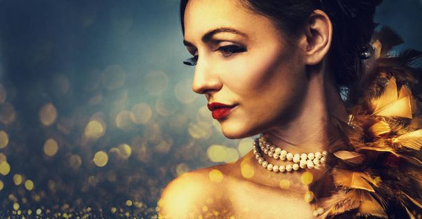 Πανέμορφη γυναίκα με πολυτελές χρυσό μακιγιάζ σε bokeh φως λαμπερό φόντο. Sensual γυναικείο πορτρέτο closeup σε ρετρό στυλ μόδας. Νυχτερινή ζωή κόμμα συνθέτουν και κομψό αξεσουάρ κοσμημάτων.  - Φωτογραφία, εικόνα