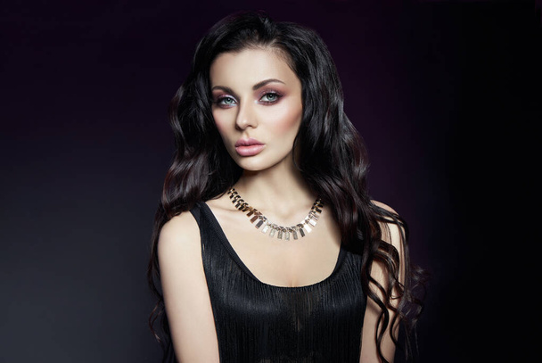 Portrait of a brunette woman with a chic hairstyle and a necklace around her neck, jewelry. Natural cosmetics and beautiful bright makeup on the face of the girl - Valokuva, kuva