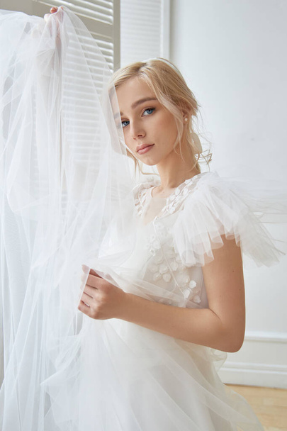 Luxurious white wedding dress on the girl's body. New collection of wedding dresses. Morning bride, a woman waiting for the groom before the wedding ceremony. Young bride in a long dress - Photo, Image