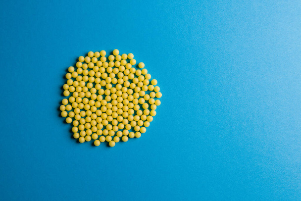 Yellow medical pills on blue background with copy space for text. Alternative homeopathy medicine, healthcare and wellness concept. Selective focus - Foto, Bild
