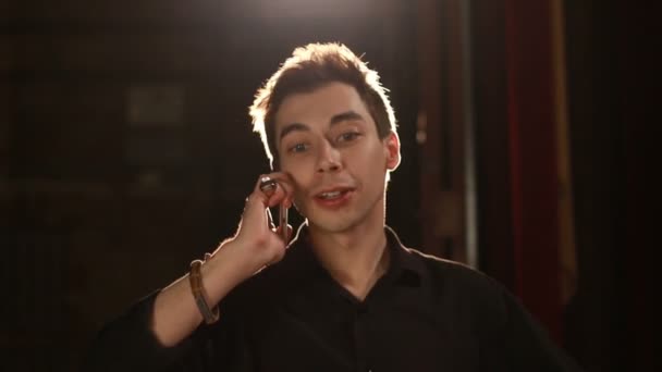 Handsome man talking phone against backlight background - Felvétel, videó