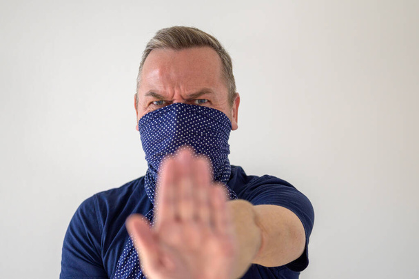 Hombre con un protector facial contra el Coronavirus o Covid-19 levantando su mano haciendo cumplir el distanciamiento social para evitar la propagación de la pandemia
 - Foto, Imagen