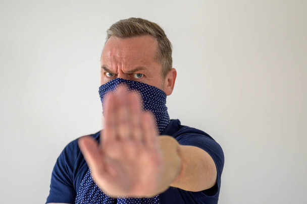 Muž s obličejovým chráničem proti koronaviru nebo Covid-19 zvedající ruku, který prosazuje sociální distancování, aby zabránil šíření pandemie. - Fotografie, Obrázek