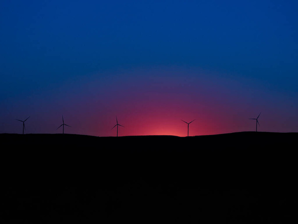 muchos molinos de viento en una puesta de sol
 - Foto, Imagen