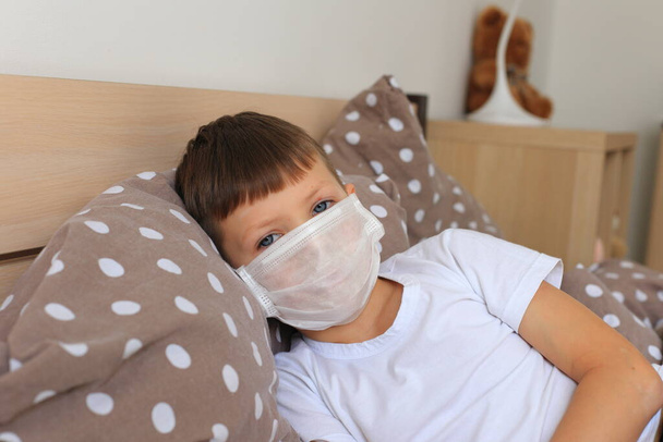 A boy in a respiratory mask sits in quarantine at home - Φωτογραφία, εικόνα