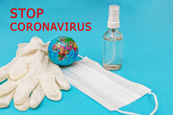 protective medical mask, gloves, alcohol disinfector, earth on a blue background. Concept, fight, prevention, quarantine against coronavirus flu infection. View from above. Flat lay. - Foto, Imagen