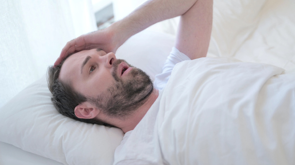 Portrait de jeune homme barbu ayant cauchemar au lit
  - Photo, image