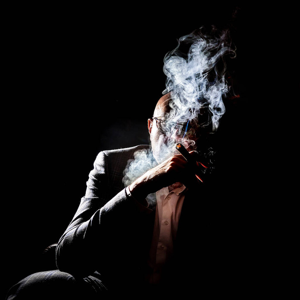 A man in a cloud of cigar smoke, creative overexposure. Man with a cigarette and smoke, art overexposure. - Photo, image