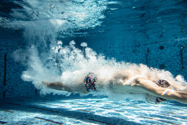 Suyun altında yüzmek için şapkalı ve gözlüklü bir erkek eğitmen. Dalış balığı. Profesyonel. - Fotoğraf, Görsel