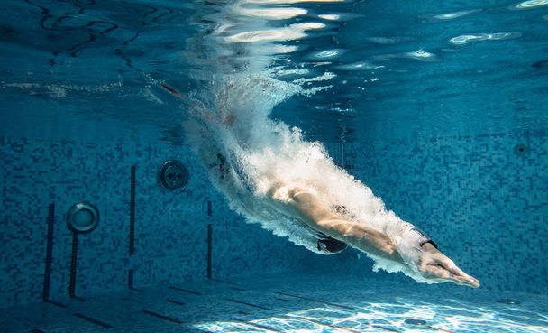 Мужчина-тренер в кепке и очках для плавания под водой. Прыжки в воду. Ональ
 - Фото, изображение