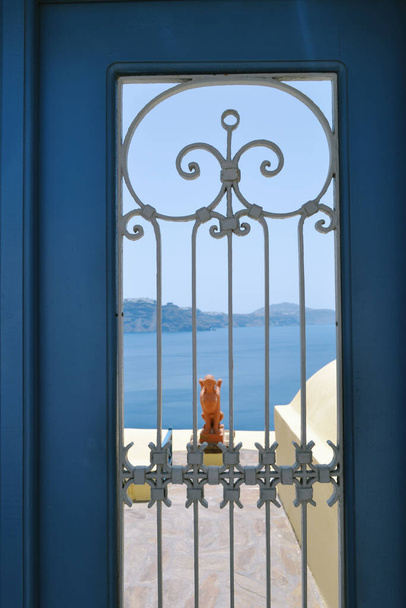 Morze przeciw niebu przez piękne niebieskie drzwi, Santorini, Grecja - Zdjęcie, obraz