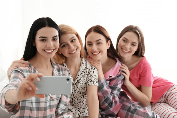 Beautiful young ladies taking selfie on bed at pamper party. Women's Day - Фото, зображення